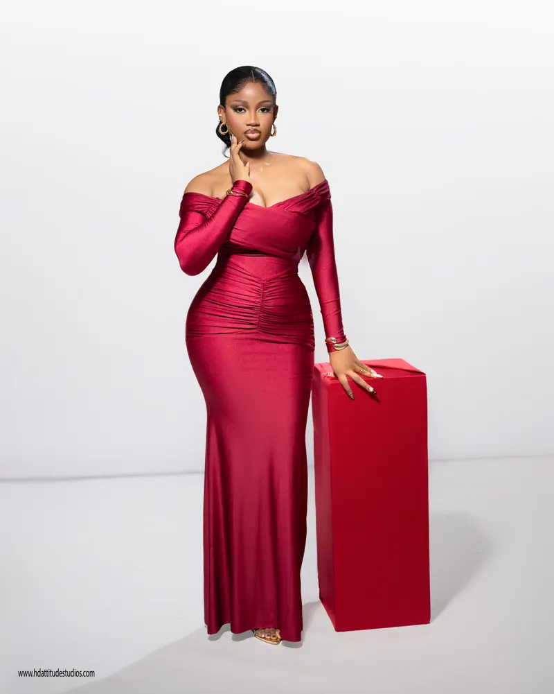 Full body standing beside the red pedestal box, no cake/candles visible