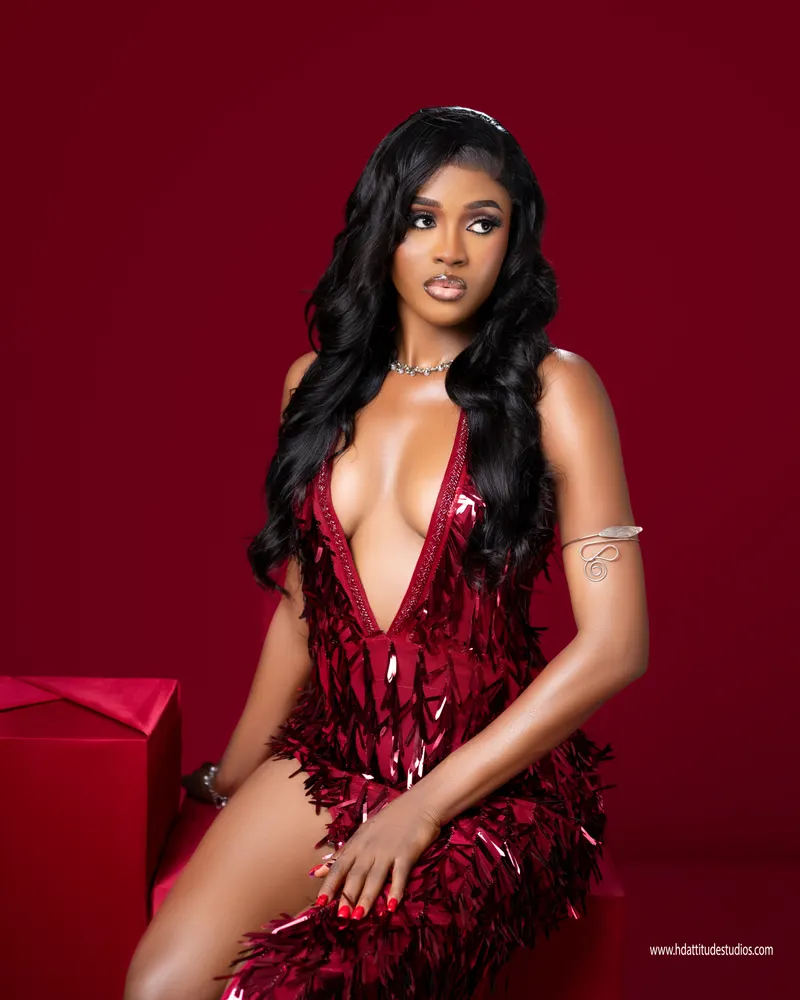 Seated variant of the same red fringe gown, red gift-box prop