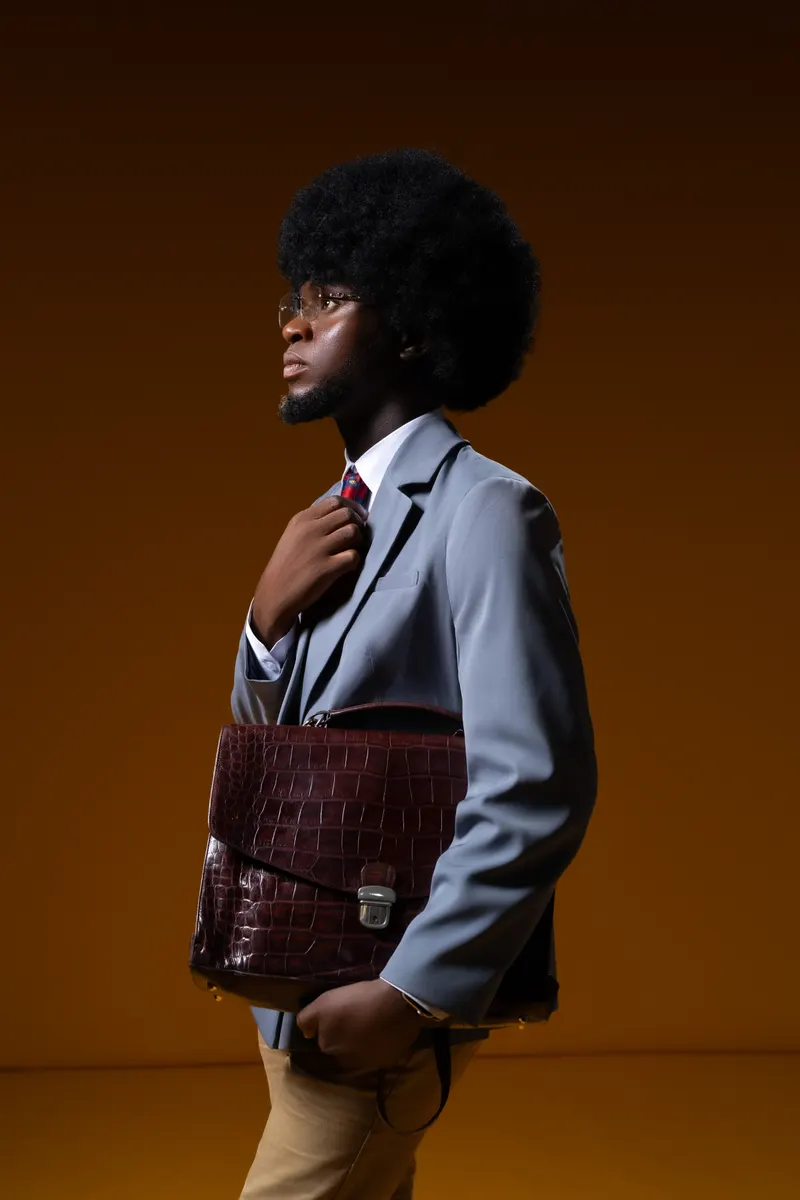 70s-inspired afro + briefcase editorial, profile silhouette, amber dramatic backdrop