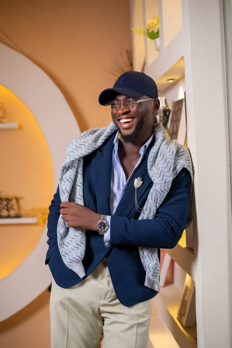 Lifestyle location portrait, navy blazer + scarf + cap, boutique interior with shelving