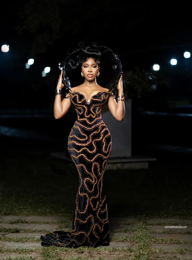 Editorial shot leaning on a metal railing at night, sculptural headpiece held aloft