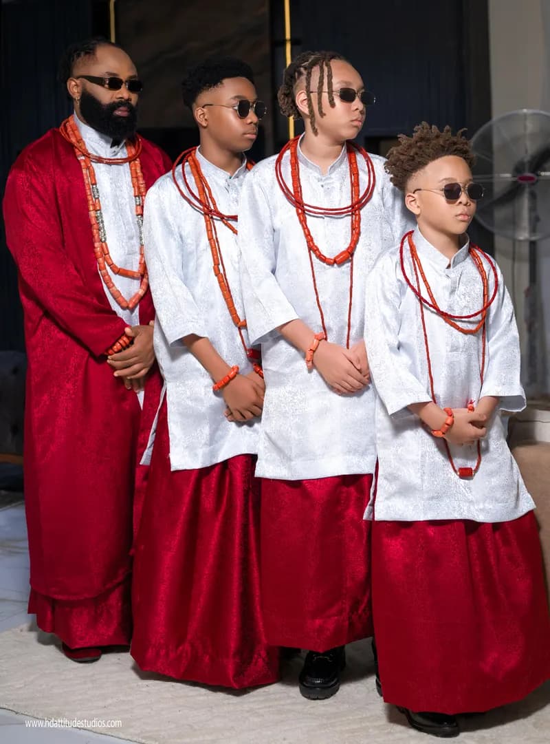 Father and three sons in white tops and red wrappers with coral necklaces
