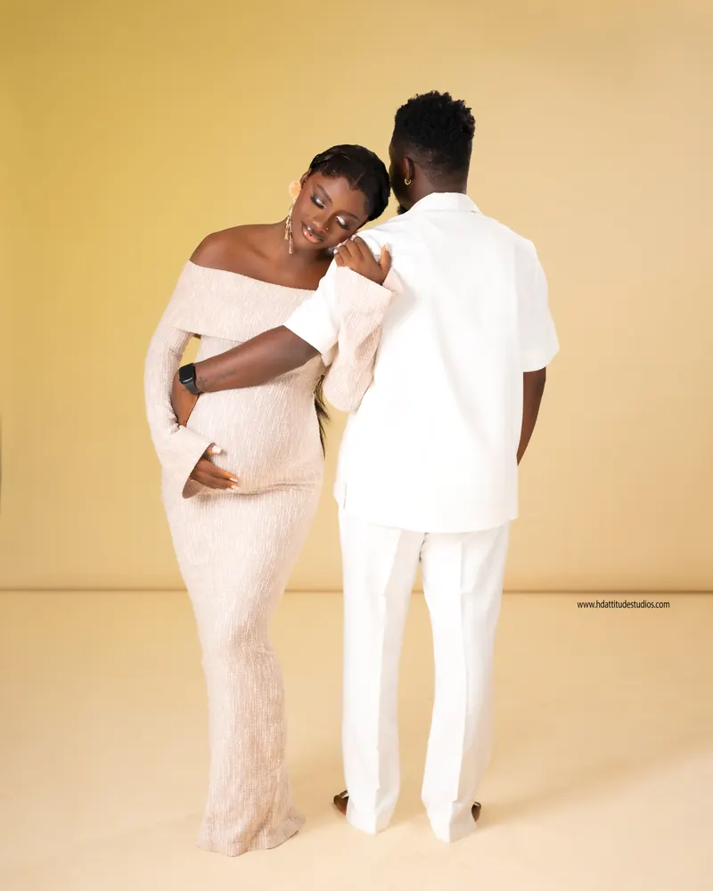 Pregnant couple shot from behind, matching neutral cream tones
