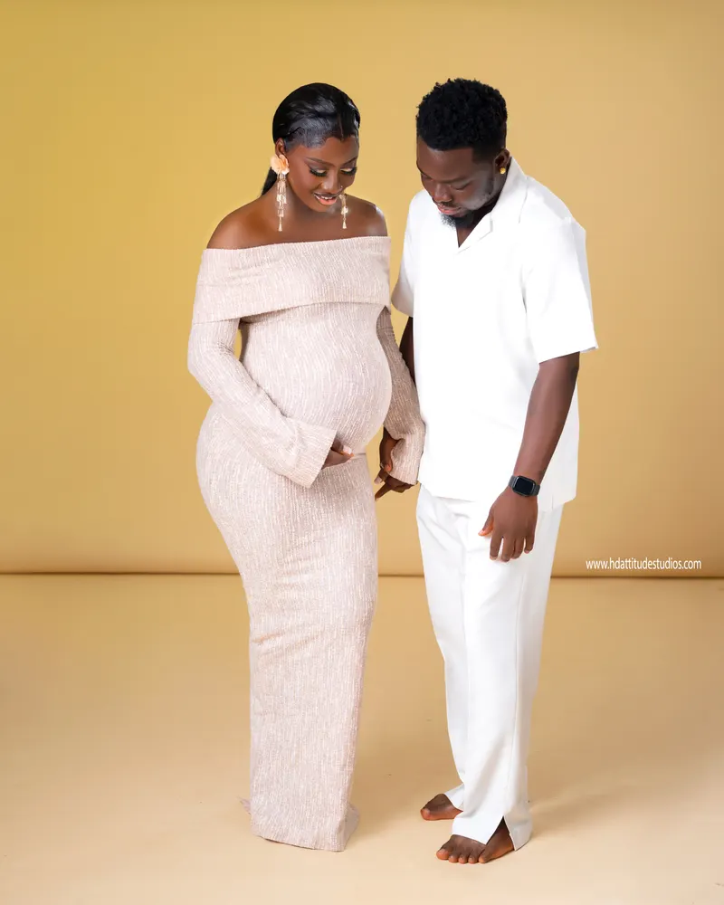 Couple facing each other, hands together over baby bump, tender moment