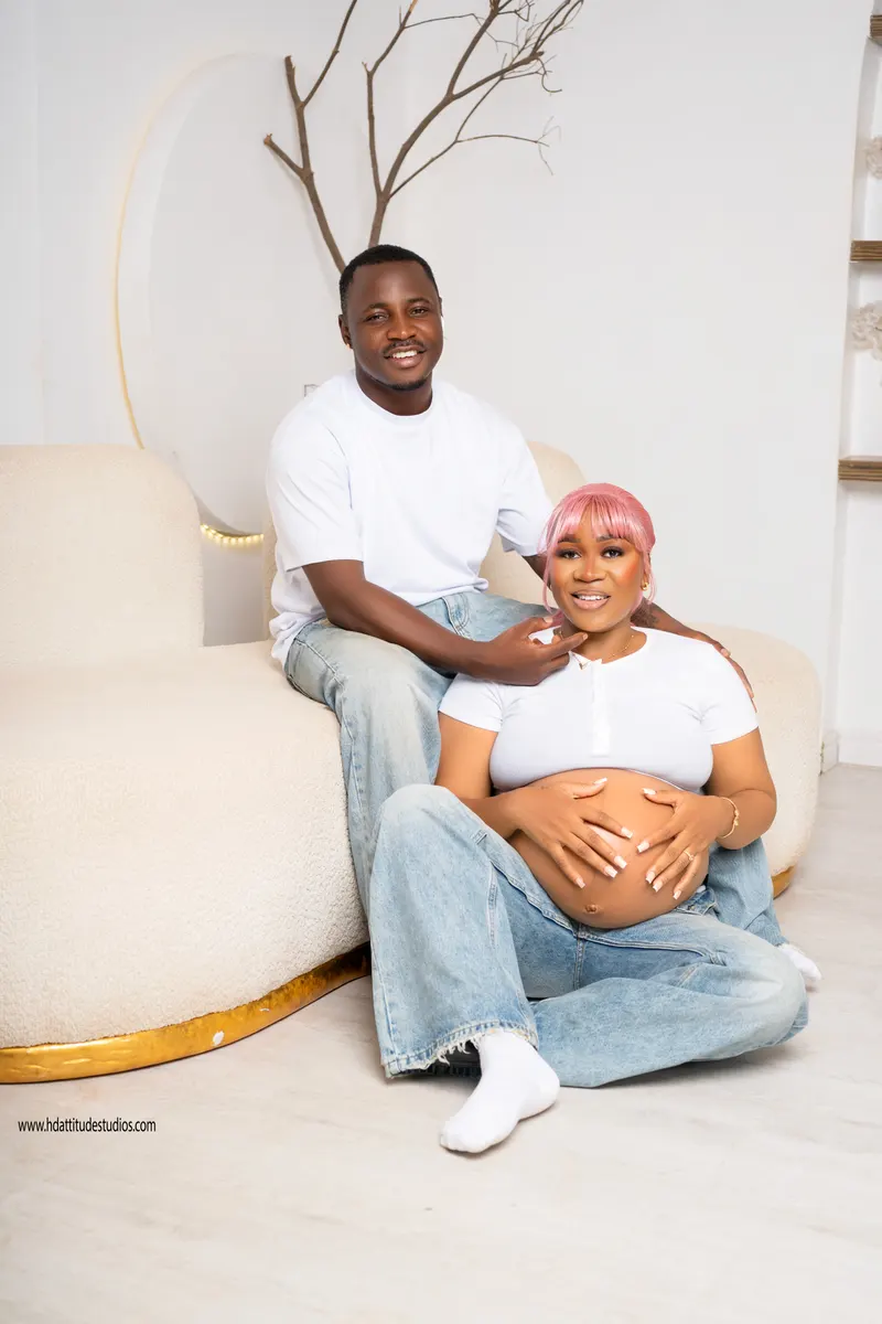 Maternity portrait, closer pose with mother's pink wig and bump cradled by both