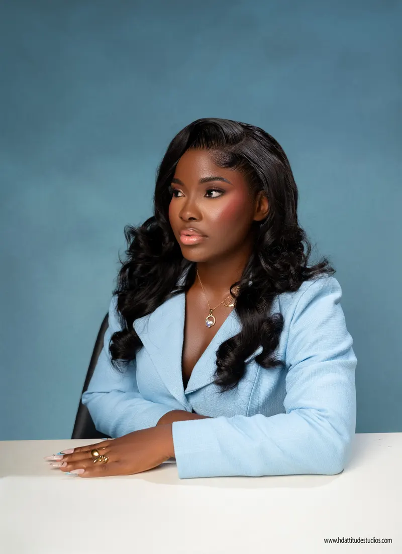 Same blue-suit set, seated at desk looking off-camera