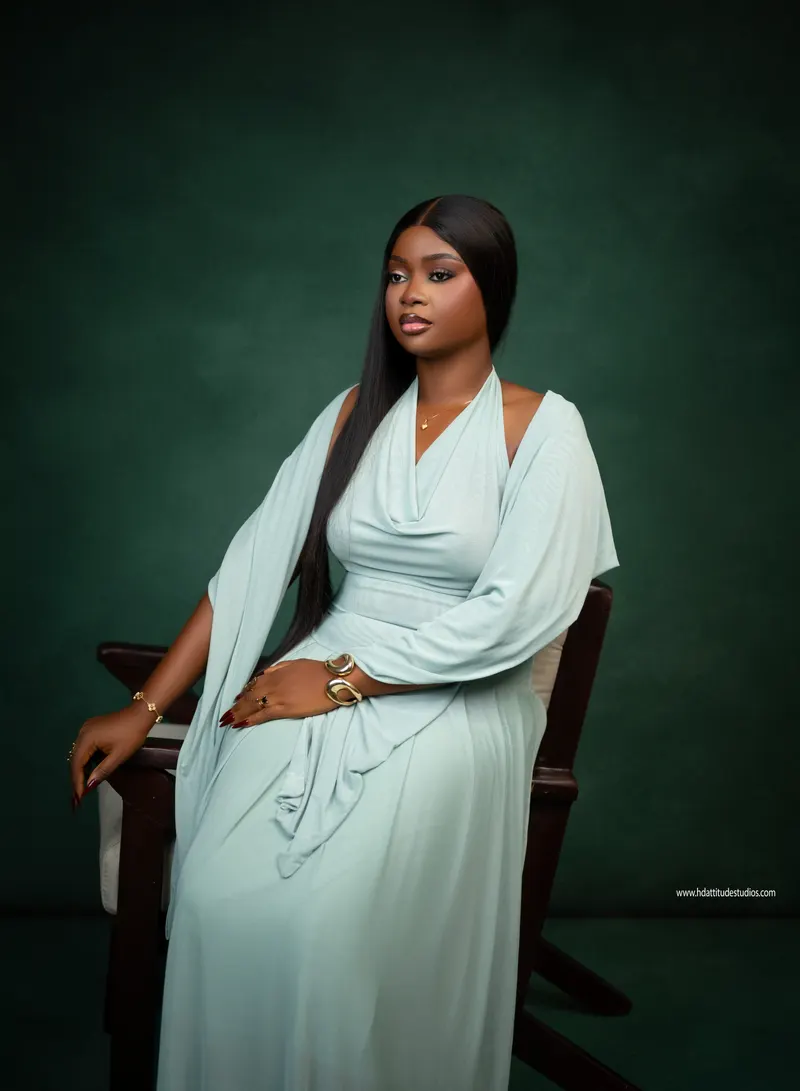 Seated portrait in mint-green draped gown against a deep green backdrop