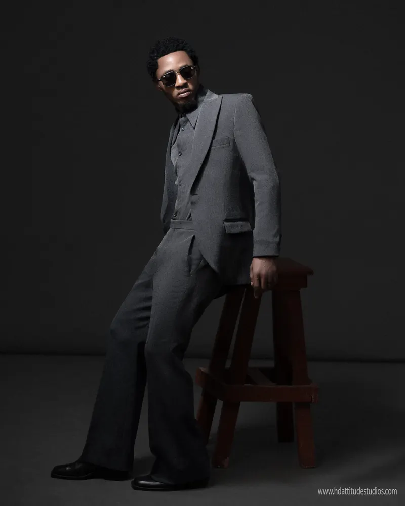 Moody chiaroscuro grey-suit portrait, single dramatic light source