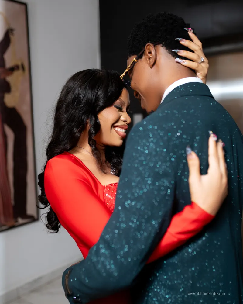 Couple close embrace, woman's hand on man's head, red dress and green sparkle blazer, gallery print on wall